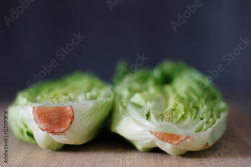 Fresh Romaine lettuce hearts on a bamboo cutting board with a dark background