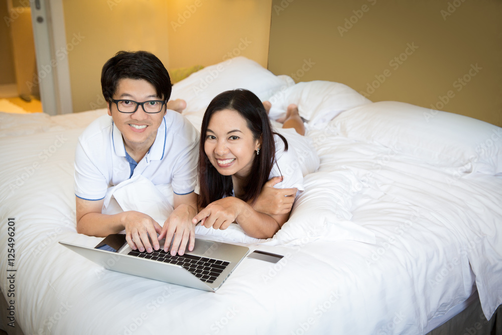Asian family using computer notebook on the bed Asian family using computer notebook on the bed