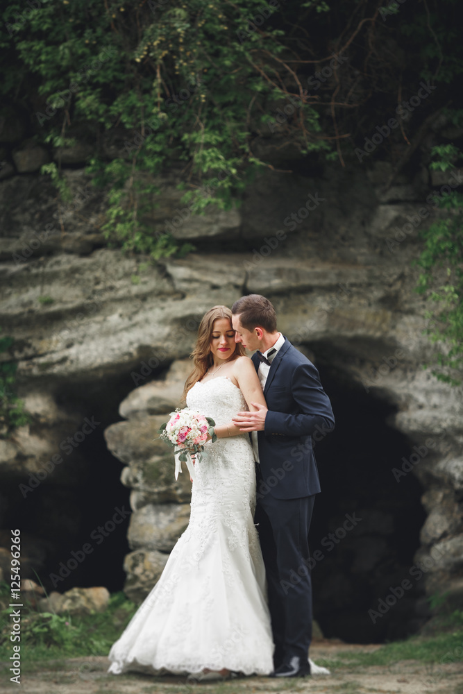 Happy wedding couple hugging and smiling each other on the background gorgeous plants in castle Happy wedding couple hugging and smiling each other on the background gorgeous plants in castle
