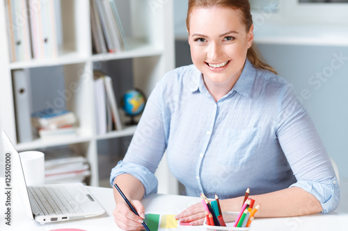 Young businesswoman working in office. Beautiful woman making notes while sitting on working place. 