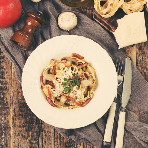 Tagliatelle with bacon cream sauce and mushrooms on wooden table photo