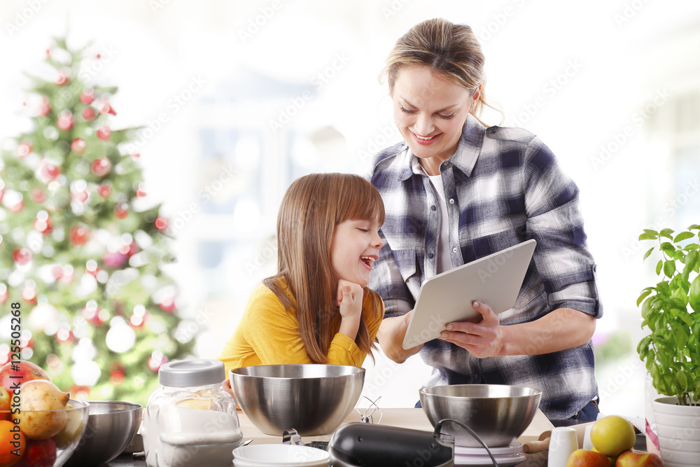 Mother and daughter at christmas.Portrait of cute daughter and her mom baking christmas cookies together in the kitchen.