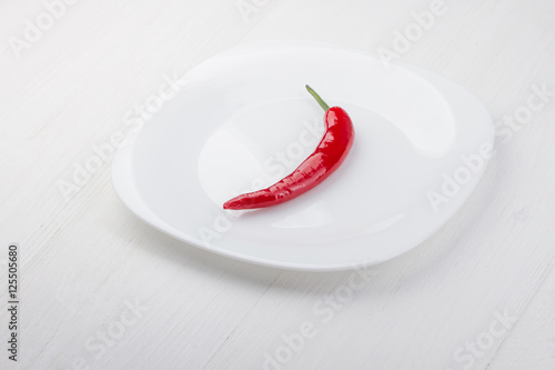 One fresh red chili peppers on a white plate