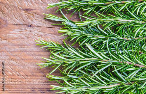Fresh rosemary on wood background copy space.