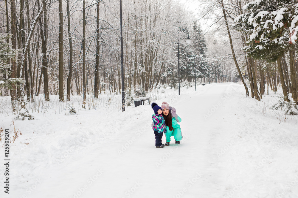 happy family mother and baby girl daughter playing and laughing in winter outdoors in the snow. happy family mother and baby girl daughter playing and laughing in winter outdoors in the snow.