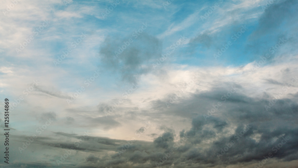 Beautiful dramatic sky with gray clouds and sunset. Dark blue feather shaped clouds in the background of bright orange sunset. Beautiful dramatic sky with gray clouds and sunset. Dark blue feather shaped clouds in the background of bright orange sunset.