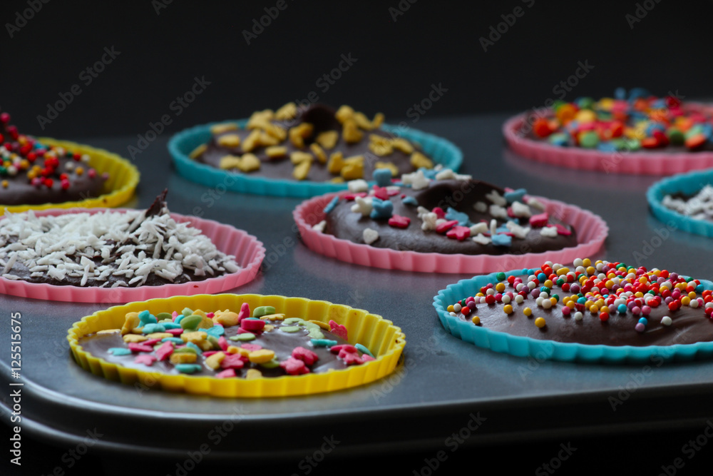 Close up of sweet homemade chocolate cupcakes with frosting on top with sugar sprinkles. Selective focus. Close up of sweet homemade chocolate cupcakes with frosting on top with sugar sprinkles. Selective focus.