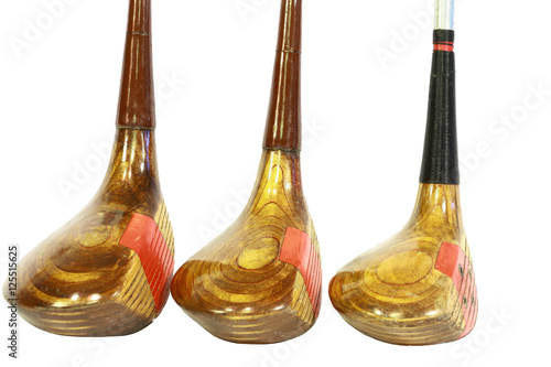 Three standing shiny antique wooden golf clubs.