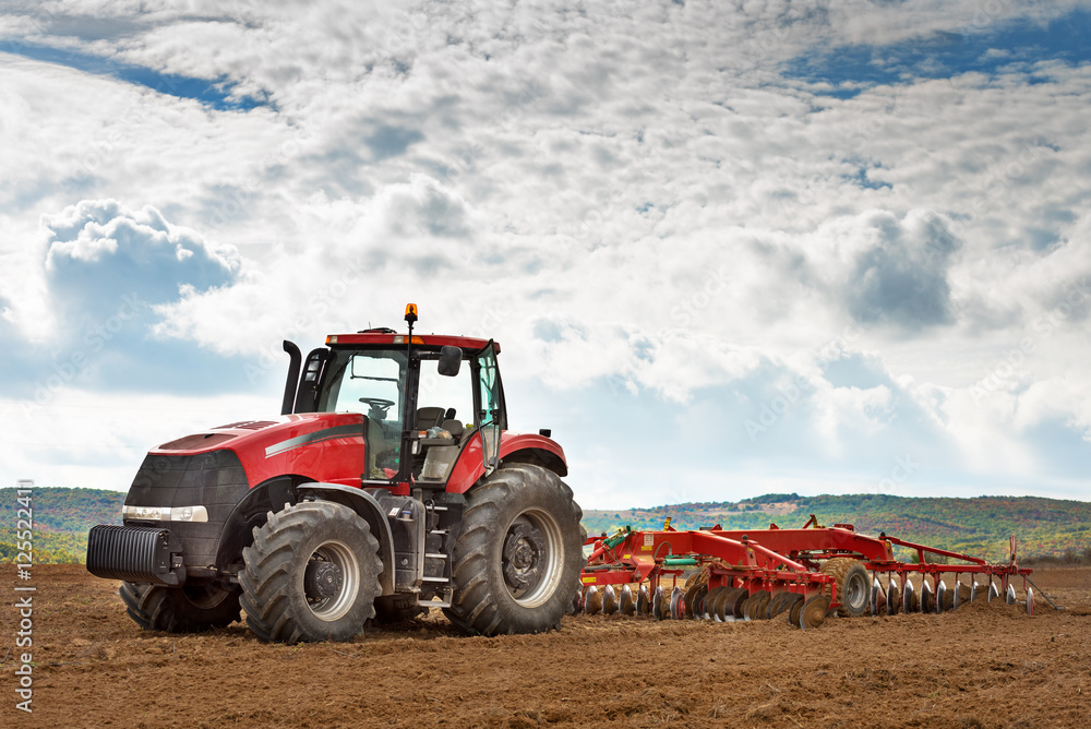 modern red tractor in the agricultural field. modern red tractor in the agricultural field.