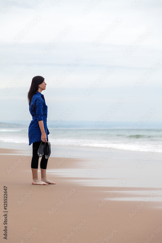 Lonely and depressed woman watching the sea in a deserted beach on an Autumn day. Lonely and depressed woman watching the sea in a deserted beach on an Autumn day.