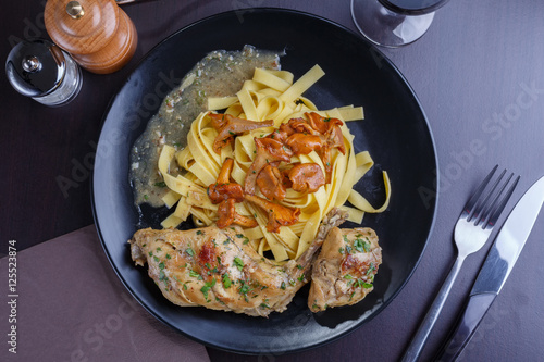 Tagliatelle with chanterelles and stewed rabbit on black terelke. side and top view. Italian pasta homemade food. setout photo