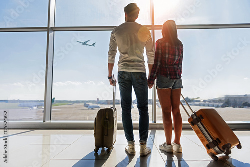 Dreamful loving couple looking at flying plane photo