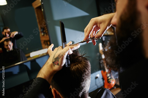 The Barber man in the process of cutting the client a pair of scissors in the Barbershop