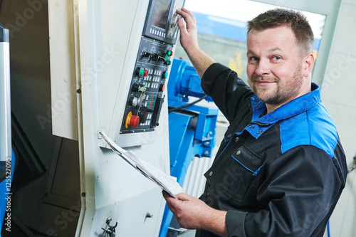 Konstfotografi industrial worker operating cnc turning machine in metal machining industry