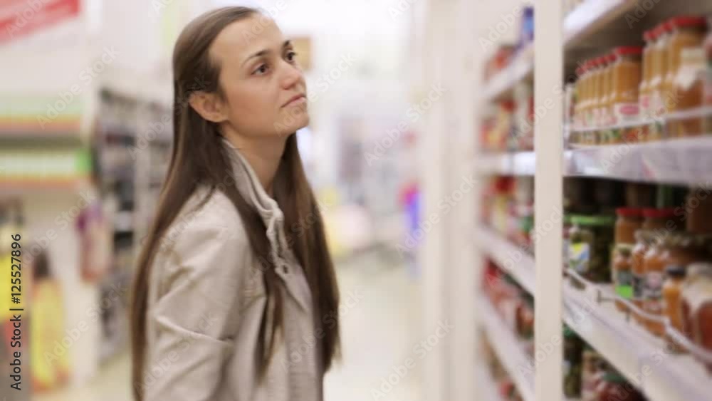 Young woman is choosing sauce in jar at the shopping center. Young woman is choosing sauce in jar at the shopping center.