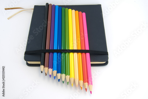 sketch book and colored pencils isolated on white background