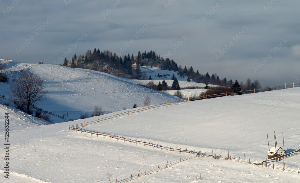 Fenced pastures in the winter in the mountains at sunrise above the clouds. Winter landscape.