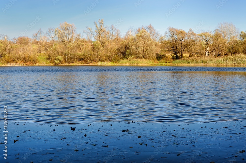 Blue lake waters and leafless trees on banks in autumn Blue lake waters and leafless trees on banks in autumn