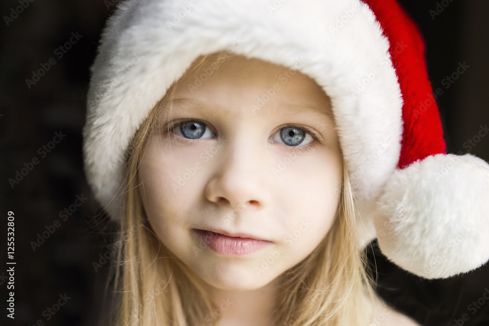 Portrait of cute girl in Santa hat against black background Portrait of cute girl in Santa hat against black background