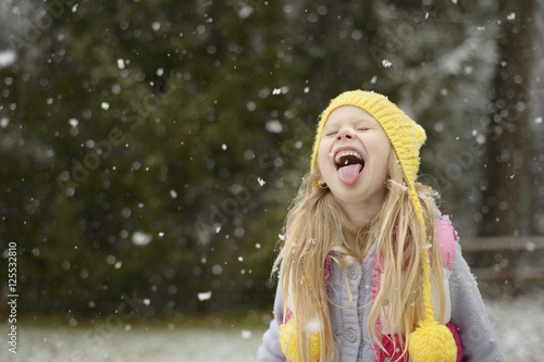 Playful girl sticking out tongue during snowfall