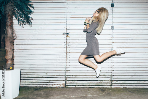 Young woman jumping in front of white wall   © Astarot