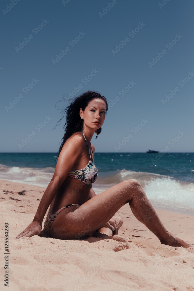 Beautiful woman in bikini on the sunny beach outdoors background