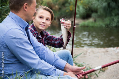 Portrait of laughing father with son having fish