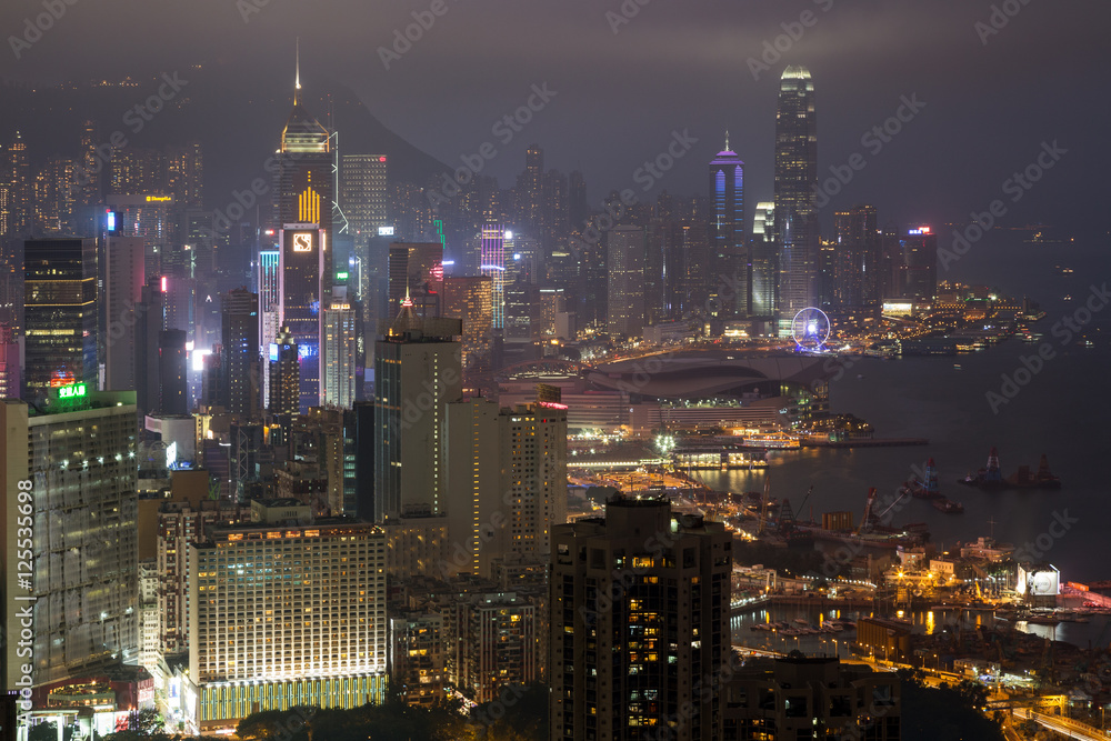 Lit skyscrapers and other buildings on Hong Kong Island in Hong Kong, China, viewed from the Braemar Hill on a foggy and cloudy evening. 