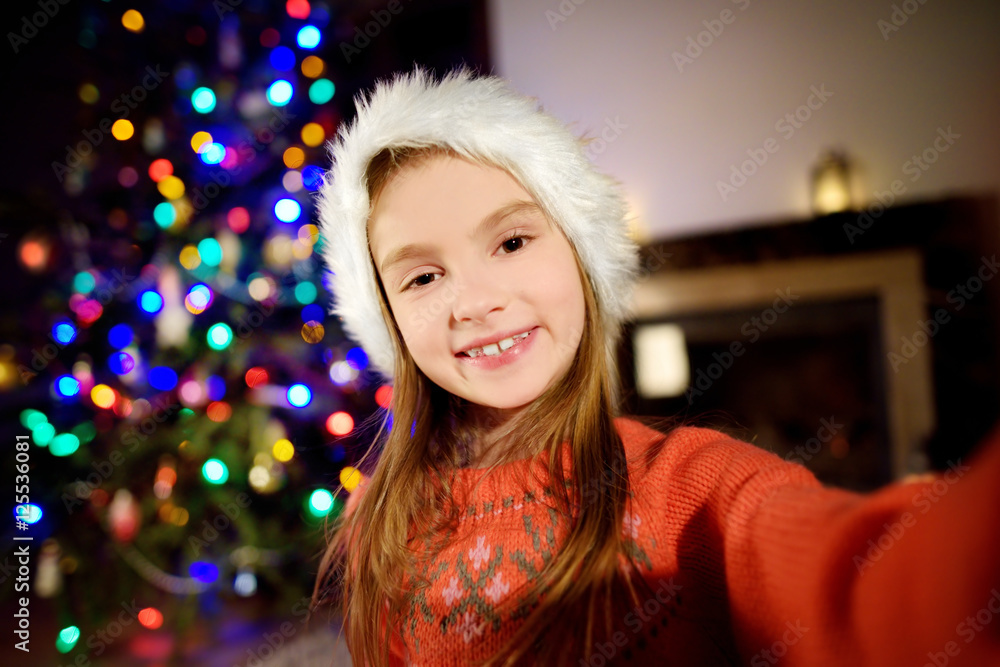 Happy little girl taking a selfie by a decorated Xmas tree Happy little girl taking a selfie by a decorated Xmas tree