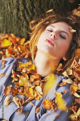 Young female lying on the leaves in the park