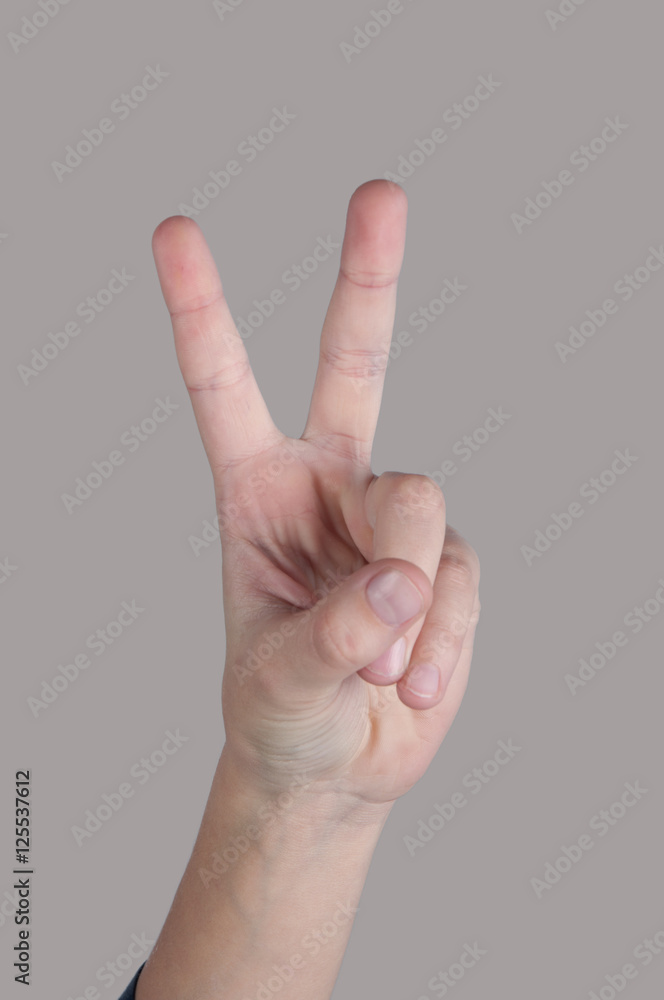 Human hand showing two fingers on grey background Human hand showing two fingers on grey background