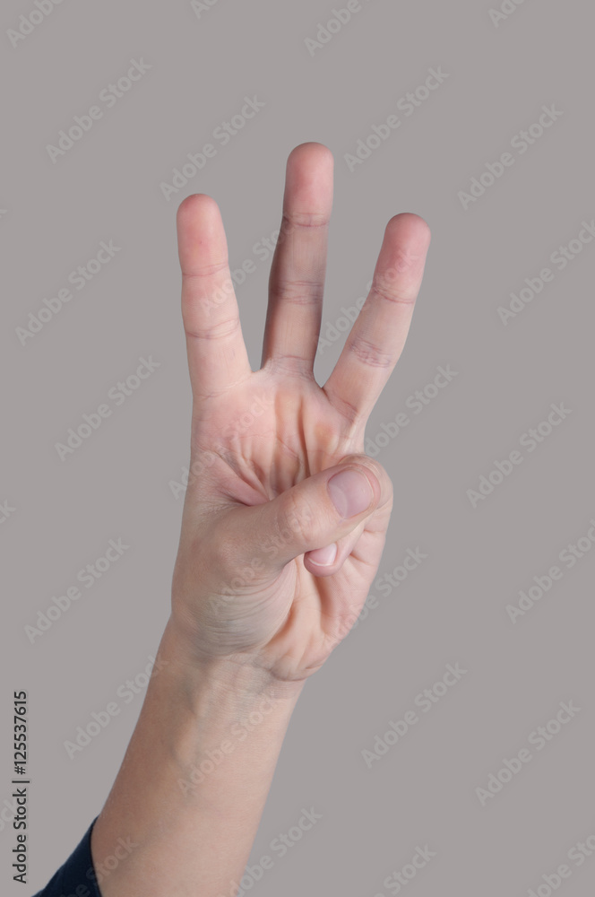 Human hand showing three fingers on grey background Human hand showing three fingers on grey background