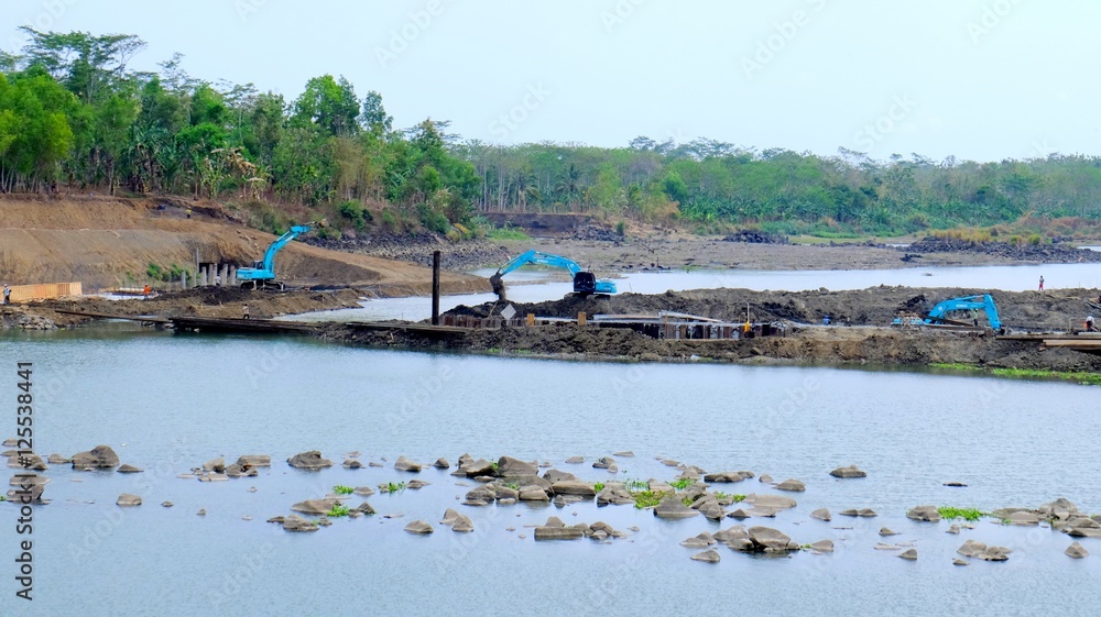 Fototapeta premium Three blue excavator working in construction site in big river