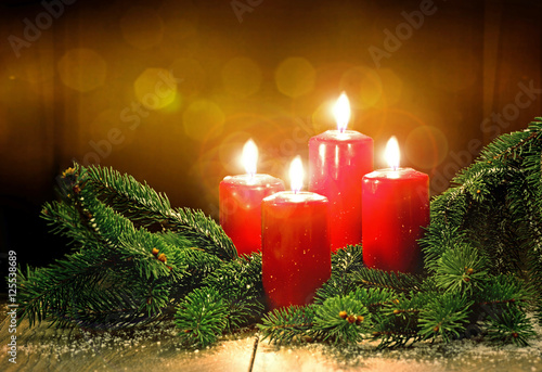 Arrangement aus vier roten Kerzen mit Tannenzweigen zum 4. Advent