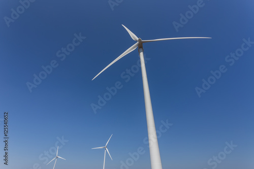 Wind generators from below, against a blue sky. © sergojpg