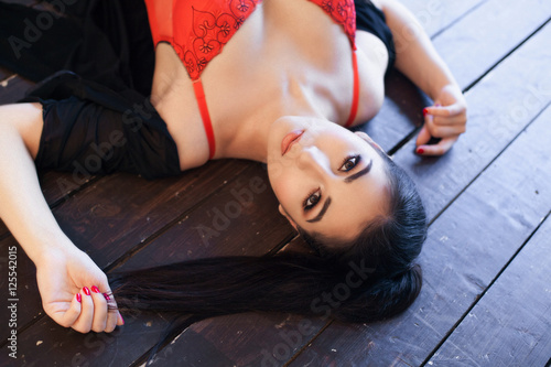 Portrait of the Young sexy woman lying on the wooden floor with eyeswide open in stockings and red corset photo