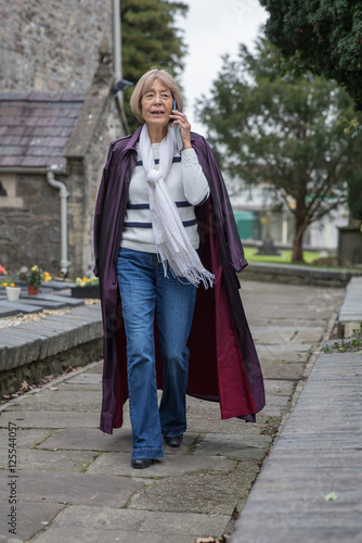 Older graceful lady walks along on her mobile phone