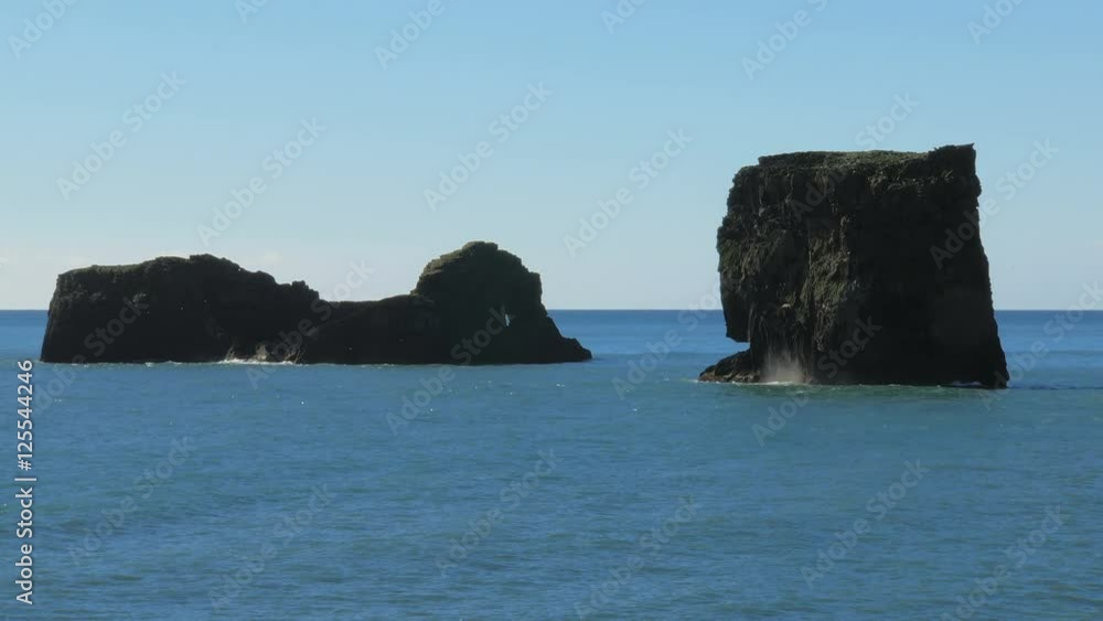 basalt rocks on a middle of ocean, in sunny day, flocks of birds flying around