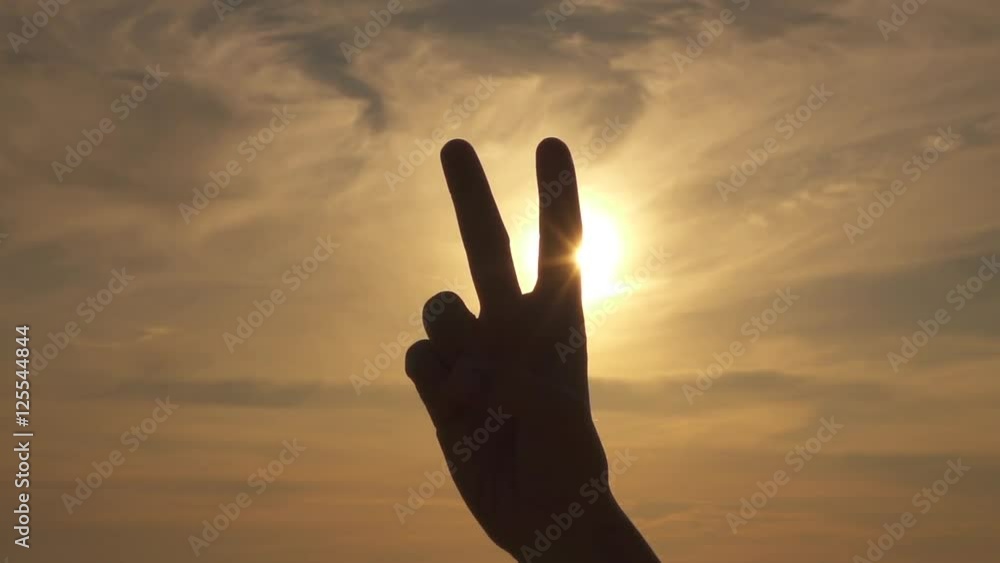 CLOSE UP: Making peace or V sign over stormy sky and golden summer sunshine CLOSE UP: Making peace or V sign over stormy sky and golden summer sunshine