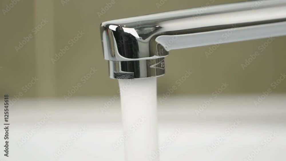 Strong stream of water pouring from the chrome tap Strong stream of water pouring from the chrome tap