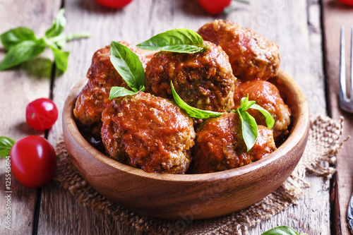 Meatballs with tomato sauce and basil, vintage wooden background photo