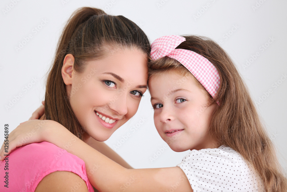 Cute girl with mother on light background