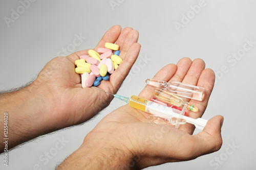 Male hands holding syringe and drugs on light background photo