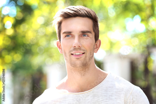 Young handsome man on blurred natural background