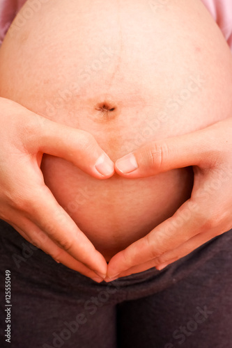 Wallpaper Mural Pregnant Woman holding her hands in a heart shape on her baby bu Torontodigital.ca