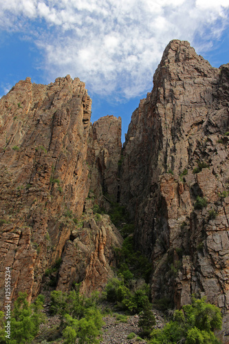 Rock walls tower high overhead, seen from the floor of the Black Canyon of the Gunnison in Colorado.