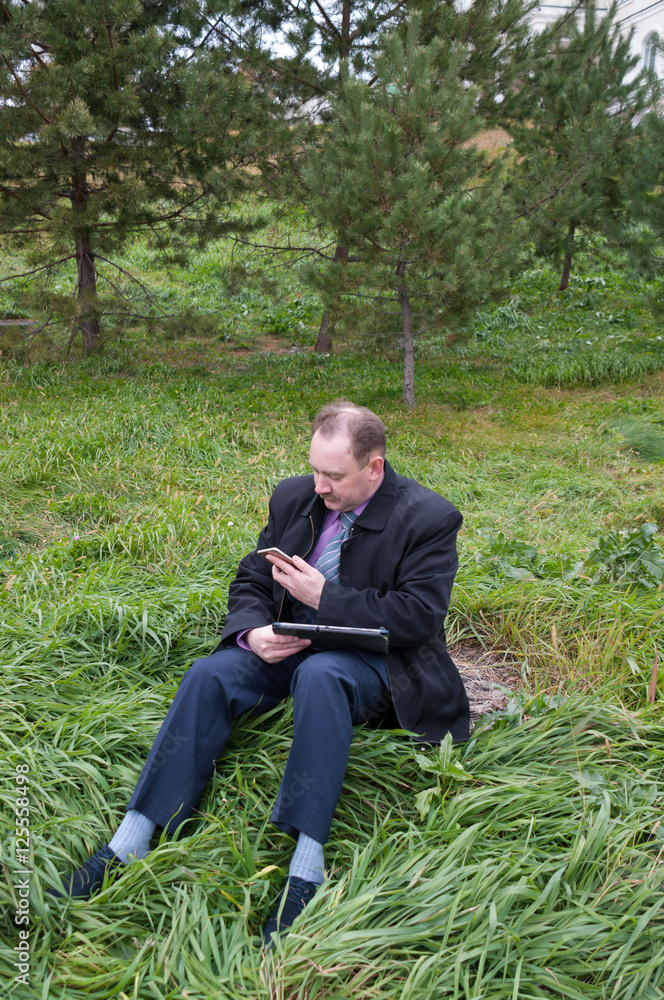 Man sits with tablet and phone in nature Man sits with tablet and phone in nature
