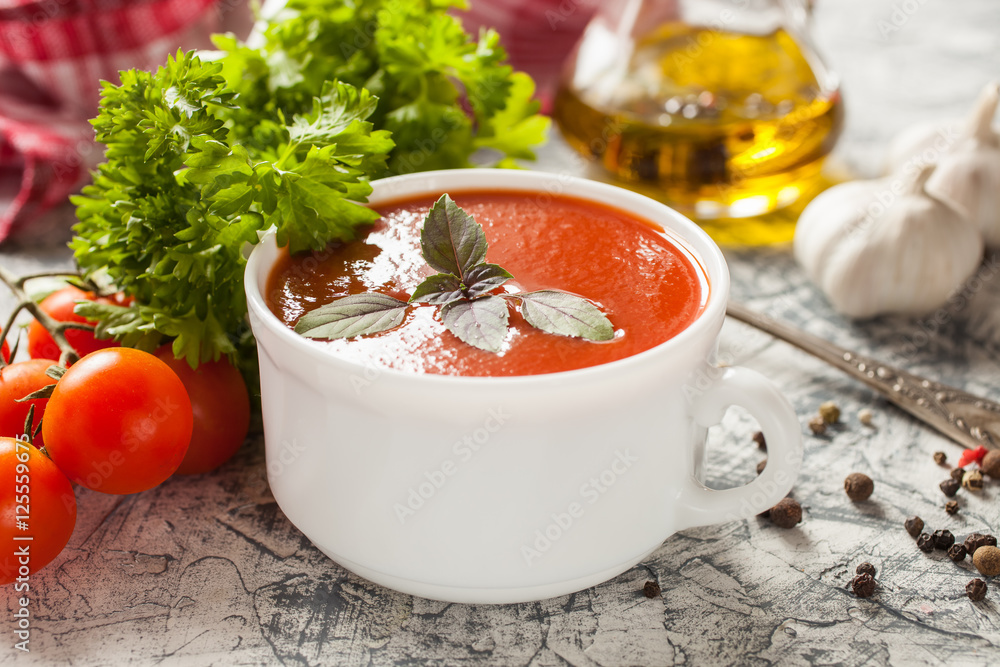 tomato soup with a basil in a bowl on a table, selective focus