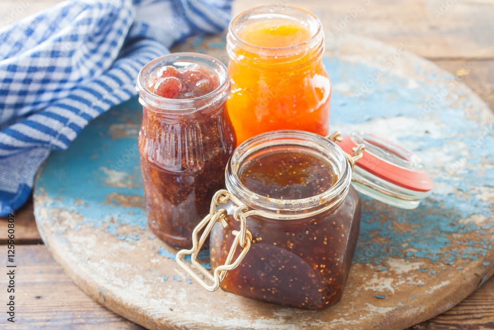 strawberry jam, a fig and apricots in jars on a table, selective focus strawberry jam, a fig and apricots in jars on a table, selective focus