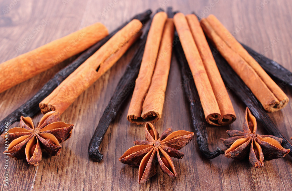 Closeup of star anise, fragrant vanilla and cinnamon on wooden surface plank Closeup of star anise, fragrant vanilla and cinnamon on wooden surface plank